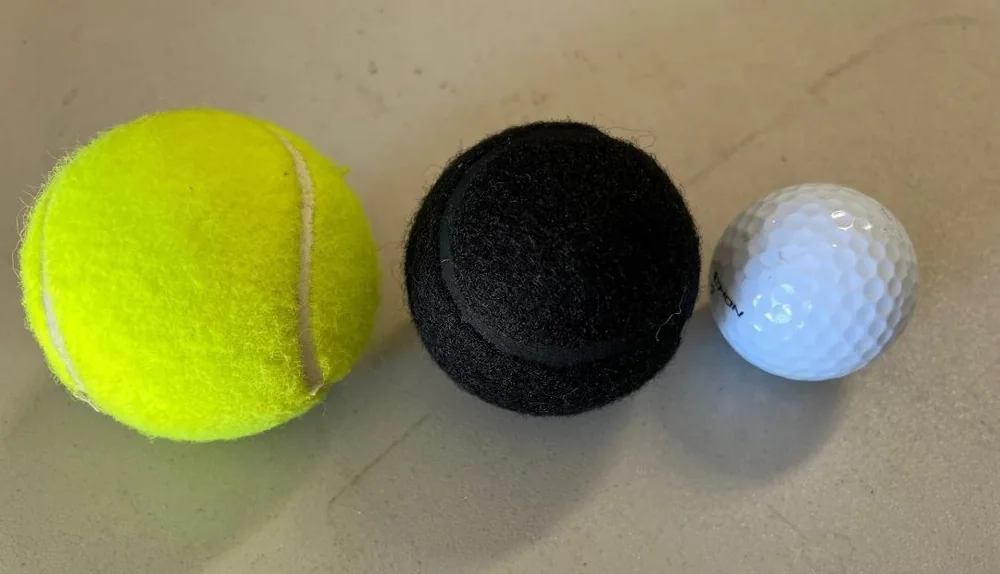 Yellow tennis ball, black tennis ball, and golf ball shown for size comparison